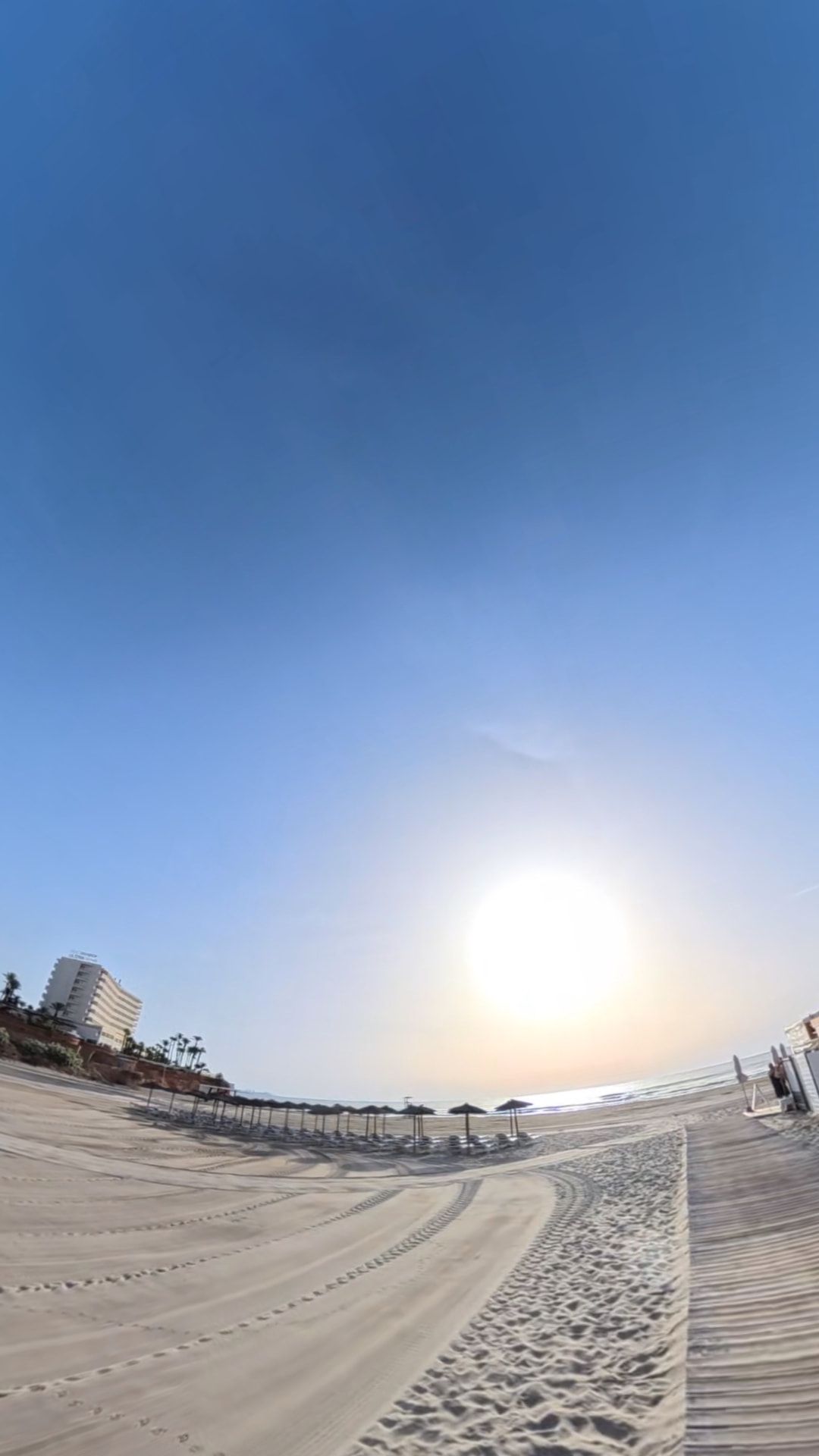 Early morning sun over an empty Orihuela Costa beach with parasols lined up on the sand