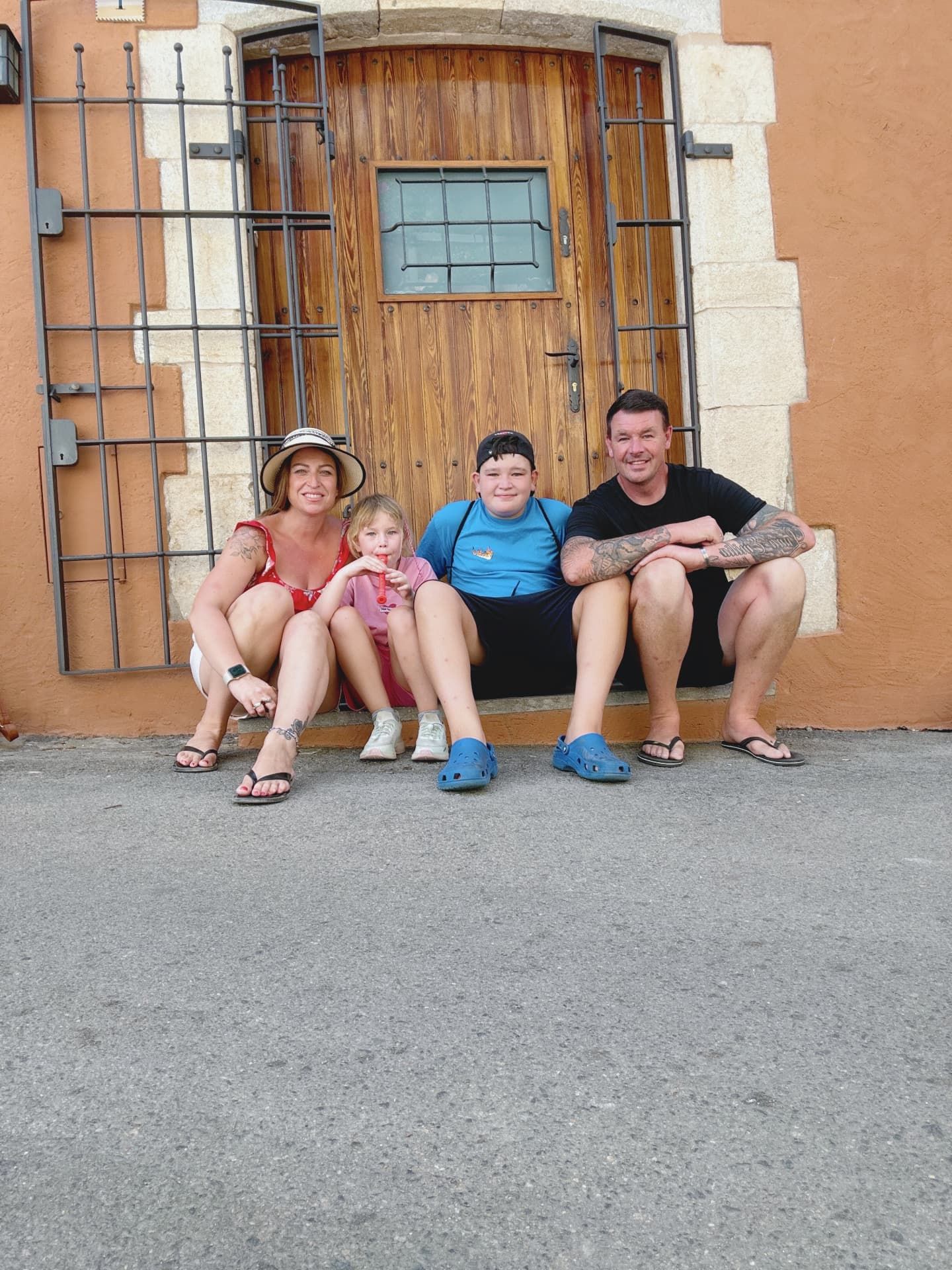 Our family of four sitting on a doorstep in a Spanish village in the summer sun