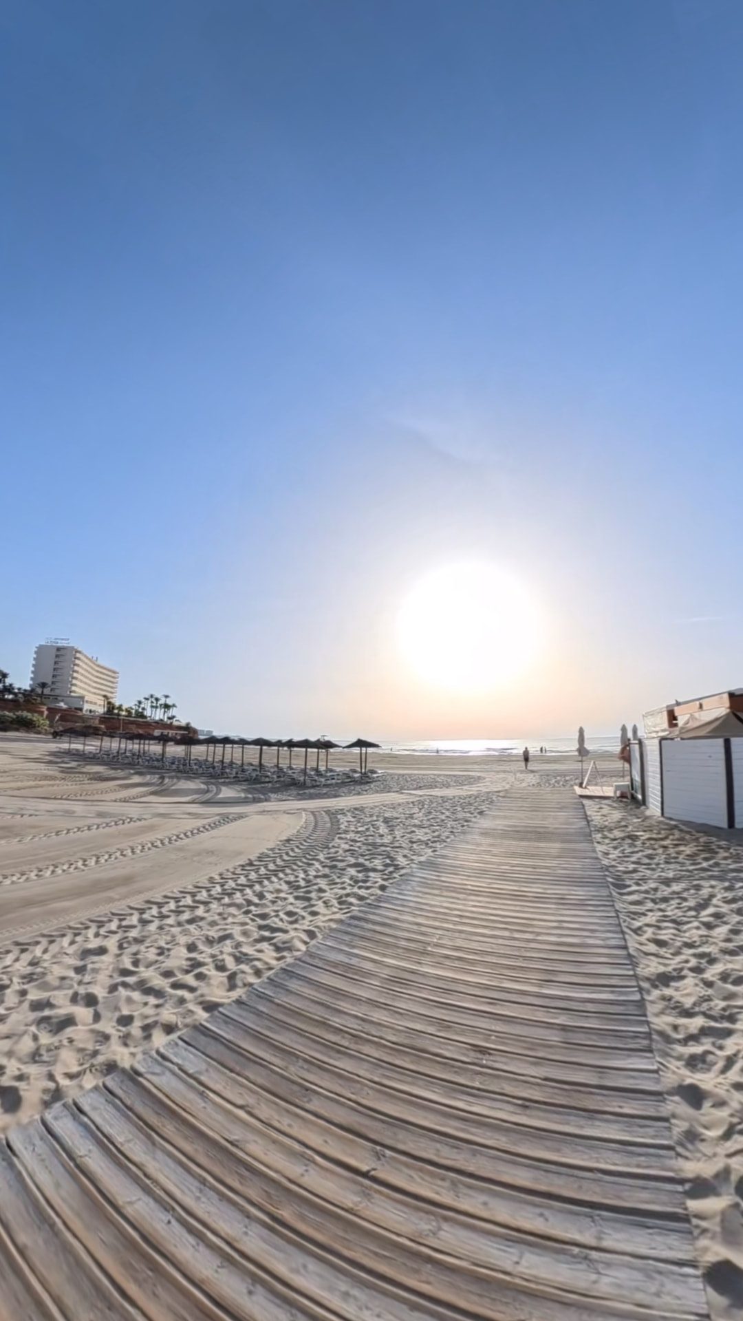 A wooden boardwalk leading across the sand to the sea at sunrise on La Zenia beach