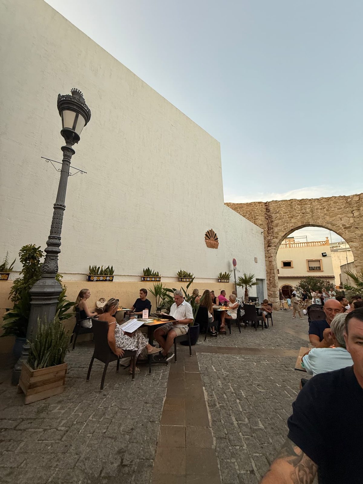 Restaurant terraces beside the old town walls and stone archway in Calpe