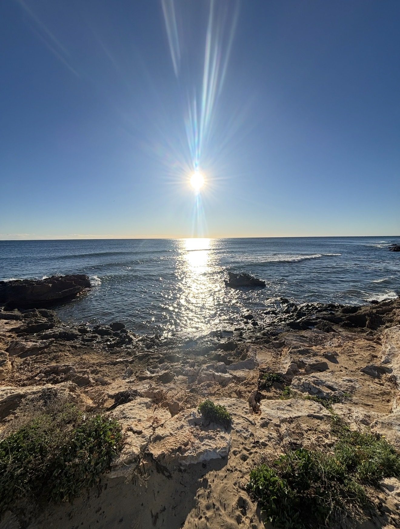 Sunrise over the rocky shoreline and clear water of a small cove on the Orihuela Costa