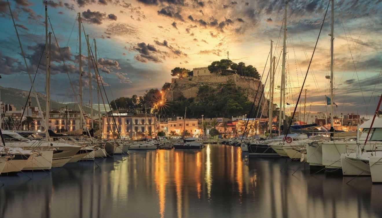 Yachts moored in Dénia marina at sunset with the hilltop castle behind