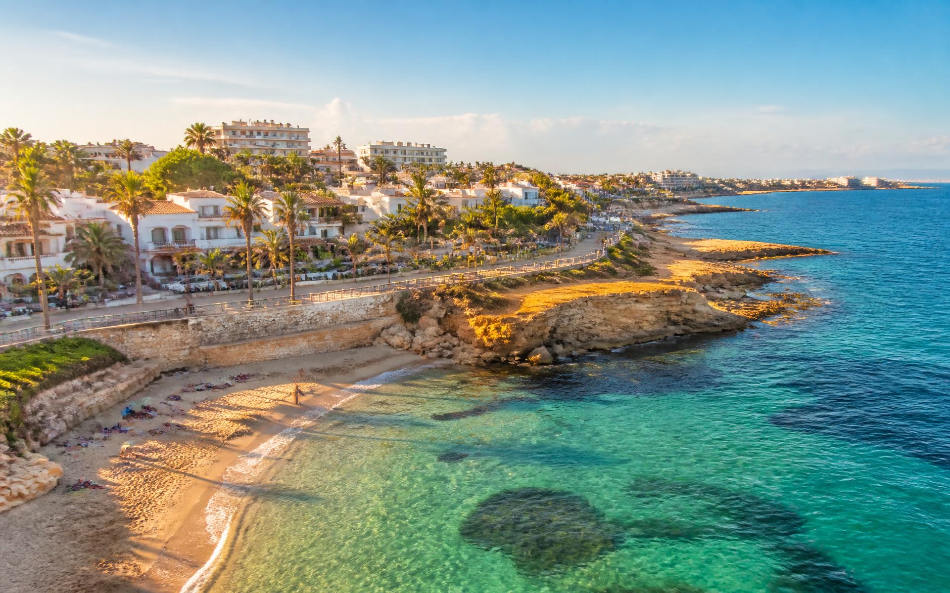 Turquoise cove and white apartments on the Orihuela Costa coastline at golden hour